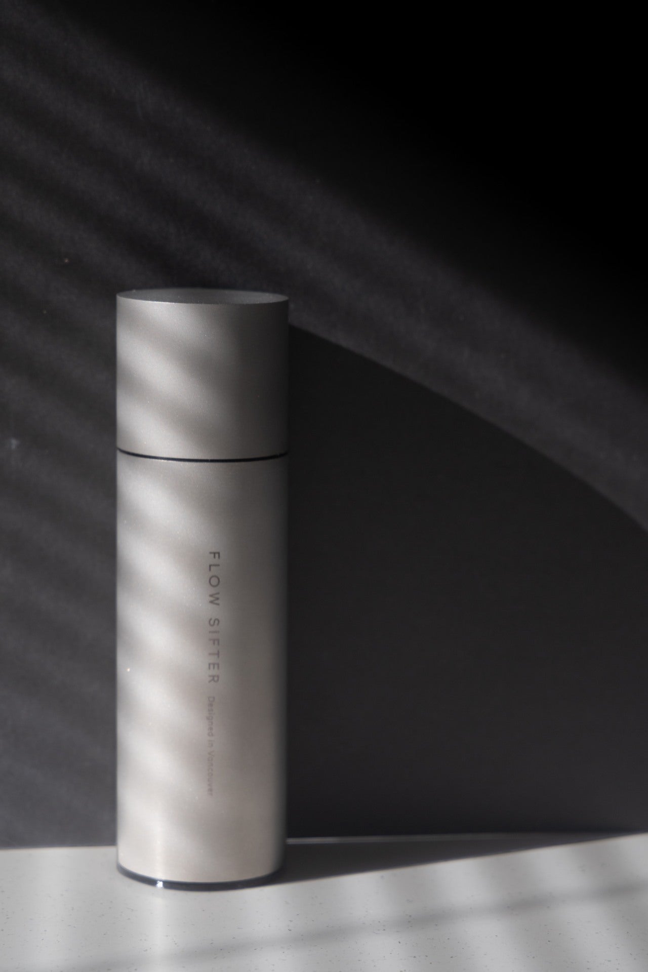 Closed Flow Sifter canister in sunlight, casting a long shadow