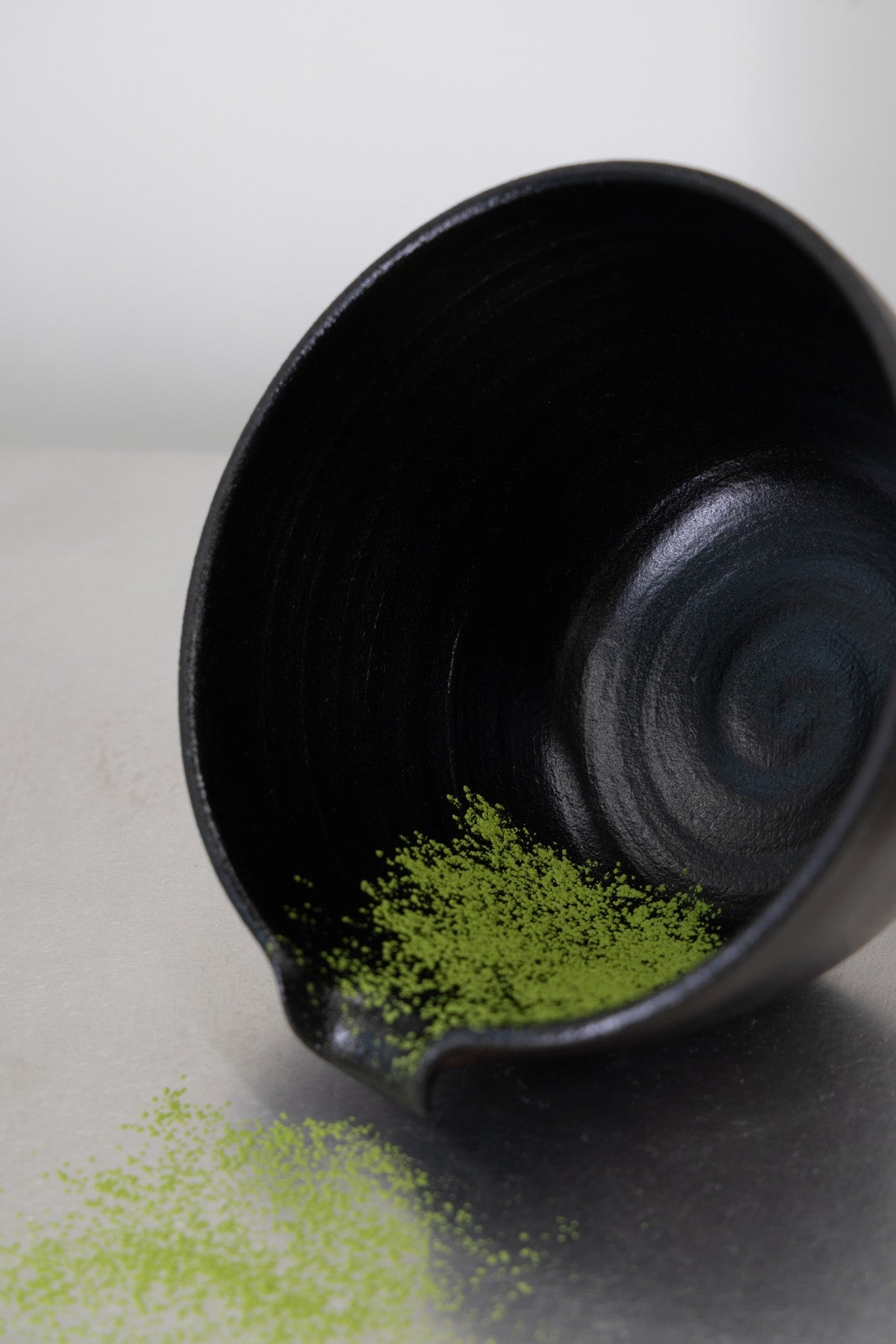 Fresh green matcha beside a black ceramic bowl